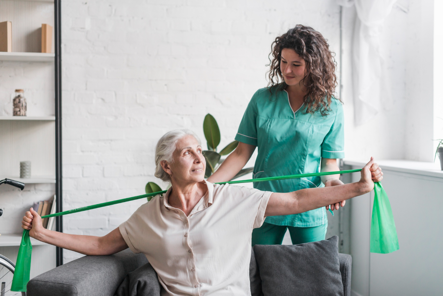 senior-woman-with-stretch-band-being-assist-by-female-physiotherapist